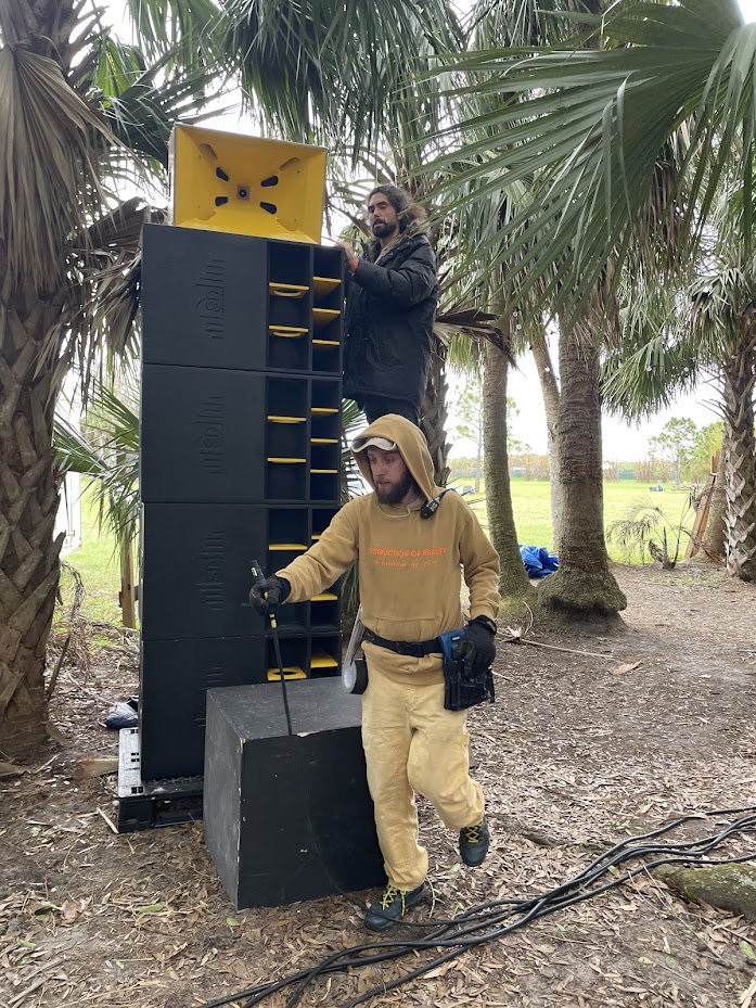 Sound Decisions crew rigging T Lounge towers during Okeechobee loadout — palm trees in background
